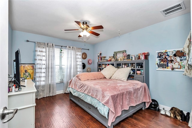 bedroom with dark wood-type flooring, a ceiling fan, visible vents, and baseboards