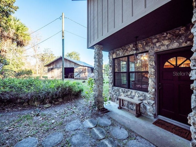 doorway to property with board and batten siding and stone siding