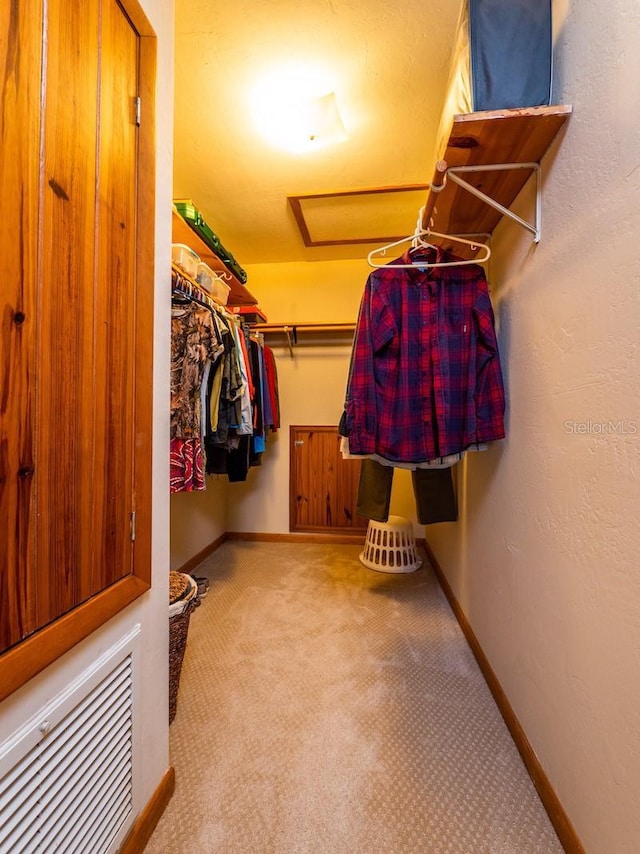 walk in closet with carpet floors and attic access