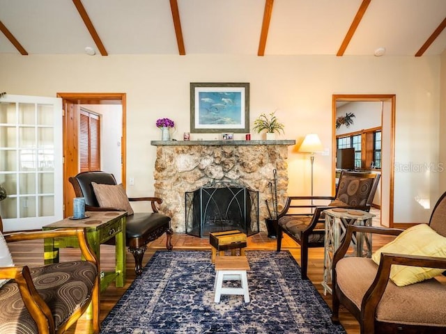 sitting room with baseboards, a fireplace, beam ceiling, and wood finished floors