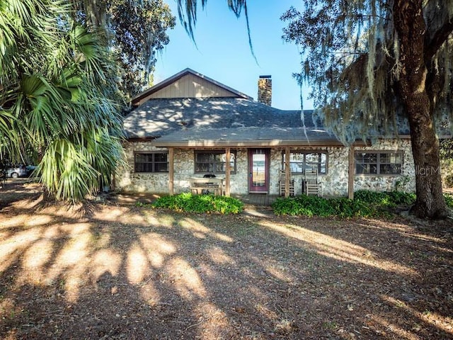 view of front of home with stone siding and a chimney