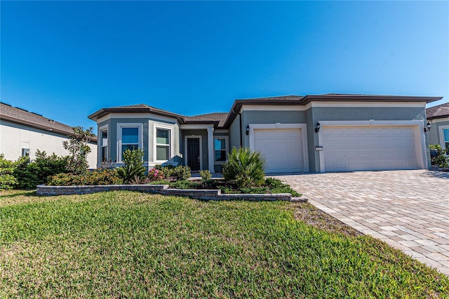 view of front of home with decorative driveway, a front yard, an attached garage, and stucco siding