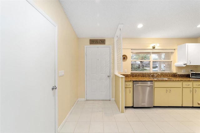 kitchen featuring a toaster, baseboards, dark stone counters, dishwasher, and a sink