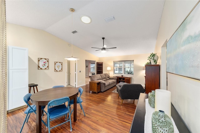 dining room with lofted ceiling, ceiling fan, wood finished floors, and visible vents