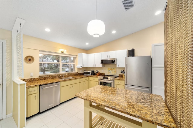 kitchen with visible vents, appliances with stainless steel finishes, range hood, dark stone countertops, and pendant lighting