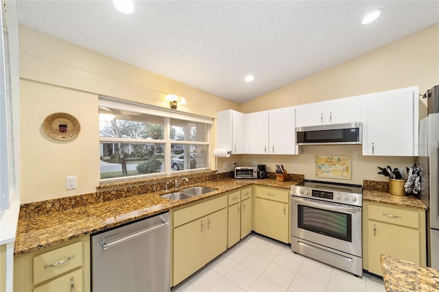 kitchen with recessed lighting, stainless steel appliances, a sink, vaulted ceiling, and dark stone countertops