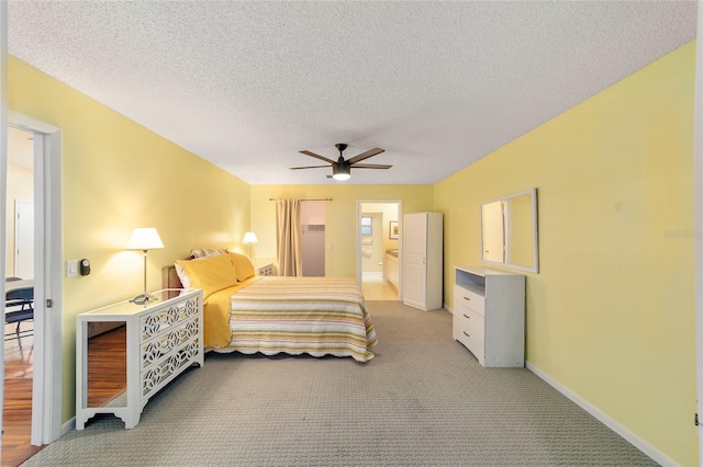 bedroom featuring a textured ceiling, ceiling fan, connected bathroom, light carpet, and baseboards