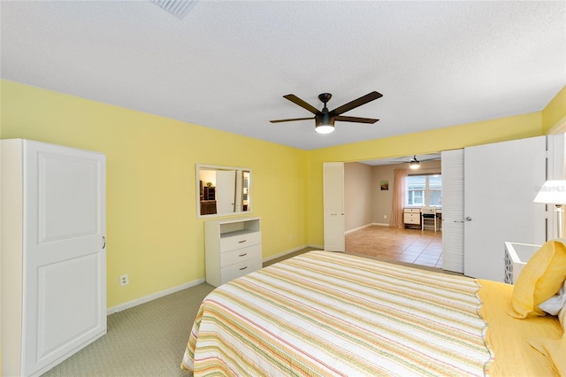 bedroom with light carpet, visible vents, baseboards, ceiling fan, and a textured ceiling