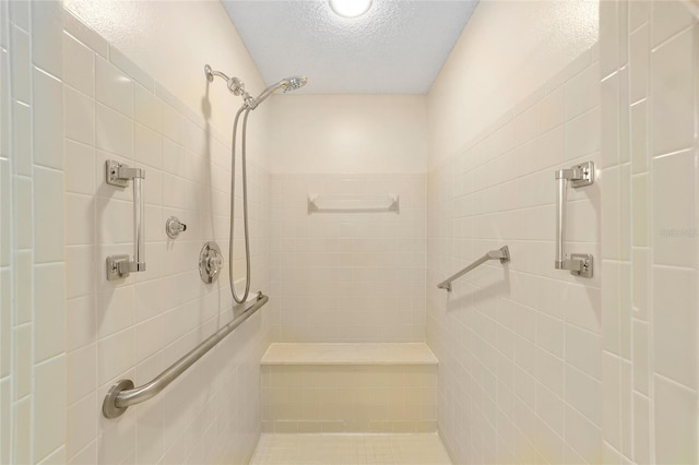 bathroom with a textured ceiling and tiled shower