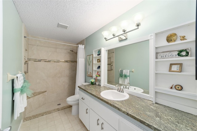 bathroom featuring visible vents, a tile shower, a textured ceiling, and vanity