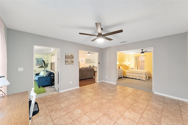 bedroom featuring light tile patterned floors, visible vents, connected bathroom, a textured ceiling, and baseboards