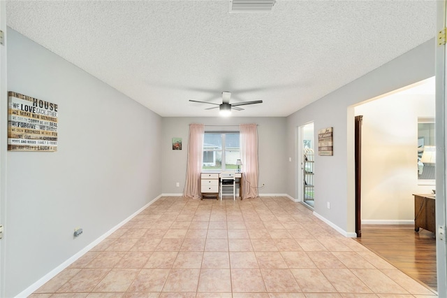 unfurnished room with light tile patterned floors, visible vents, ceiling fan, a textured ceiling, and baseboards