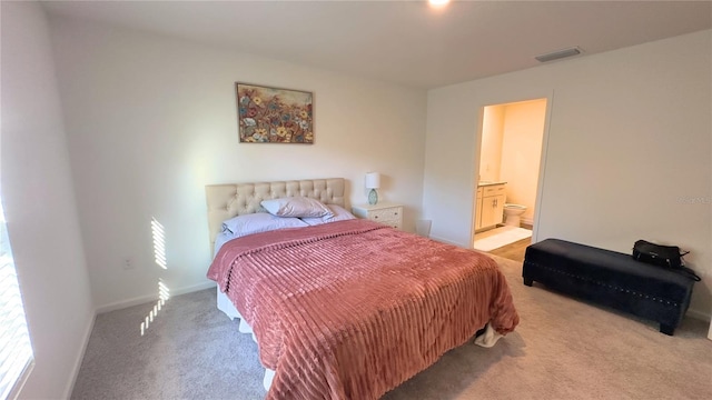 bedroom featuring ensuite bath, baseboards, visible vents, and light colored carpet