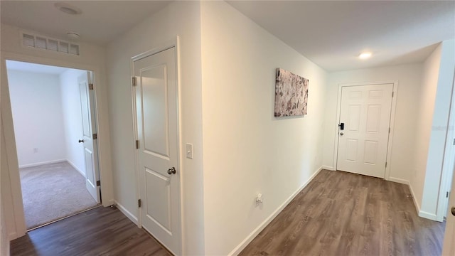 hallway with baseboards, visible vents, and wood finished floors