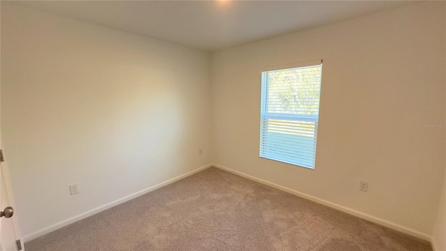 unfurnished room featuring baseboards and light colored carpet