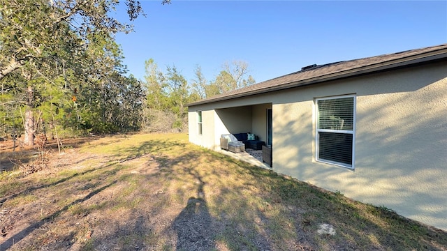 view of side of property featuring a lawn and stucco siding