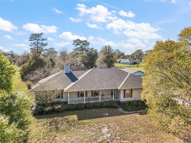 single story home featuring a porch, a shingled roof, and a chimney