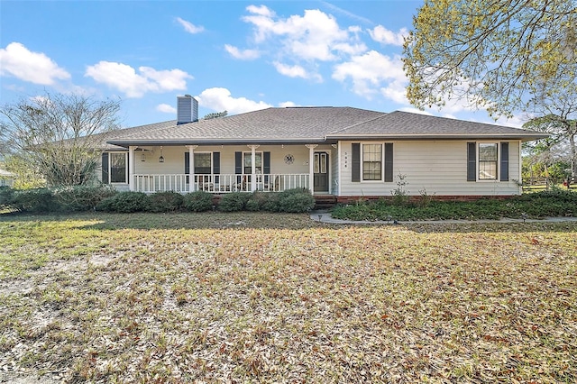 ranch-style home with a porch, a chimney, and a front yard