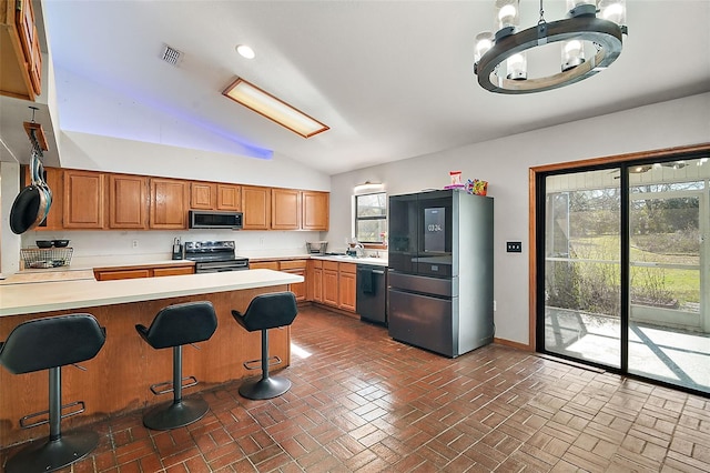 kitchen with visible vents, brown cabinetry, appliances with stainless steel finishes, a breakfast bar, and light countertops