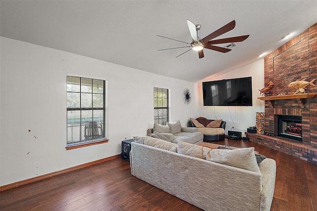 living area with dark wood-style floors, vaulted ceiling, a fireplace, and a ceiling fan