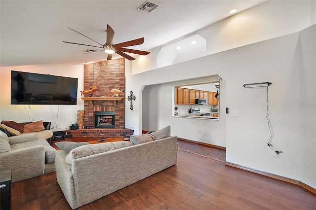 living area featuring a fireplace, wood finished floors, visible vents, a ceiling fan, and vaulted ceiling