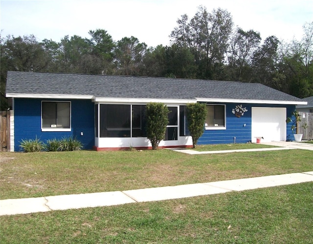 ranch-style home with roof with shingles, an attached garage, and a front lawn