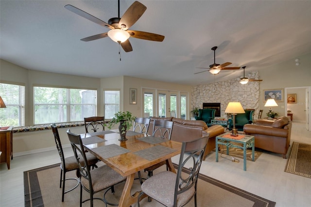 dining area with lofted ceiling, plenty of natural light, a fireplace, and baseboards