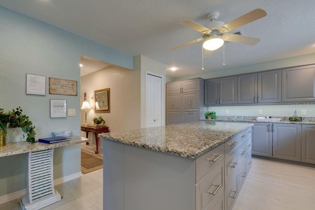 kitchen featuring light stone countertops, gray cabinetry, and a center island