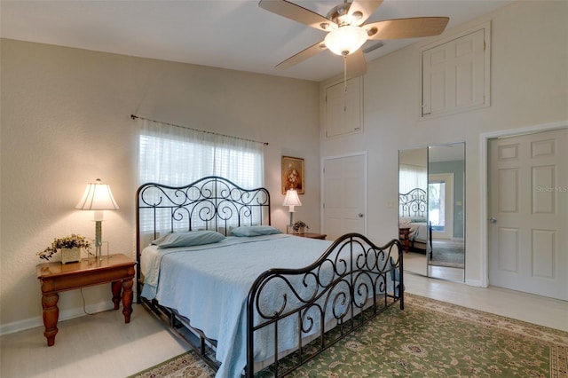 bedroom featuring a ceiling fan, baseboards, multiple windows, and a high ceiling