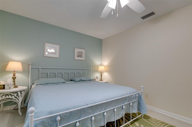 bedroom with a ceiling fan, wood finished floors, visible vents, and baseboards