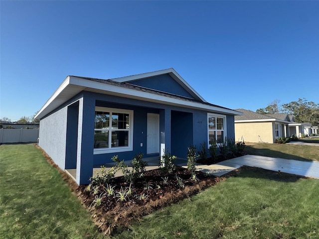 view of front of house with a front yard, fence, and stucco siding