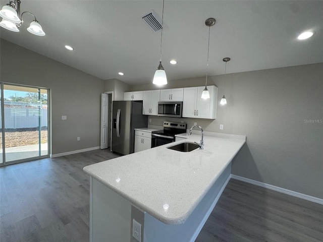 kitchen featuring pendant lighting, appliances with stainless steel finishes, white cabinets, vaulted ceiling, and a peninsula