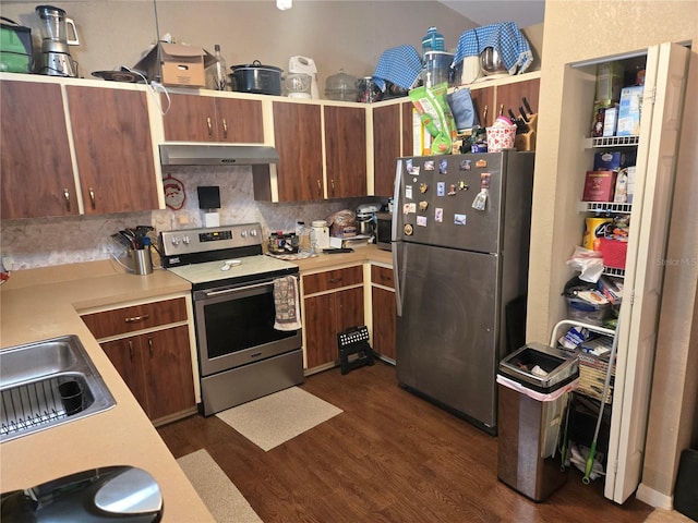 kitchen featuring stainless steel appliances, tasteful backsplash, light countertops, dark wood-type flooring, and under cabinet range hood