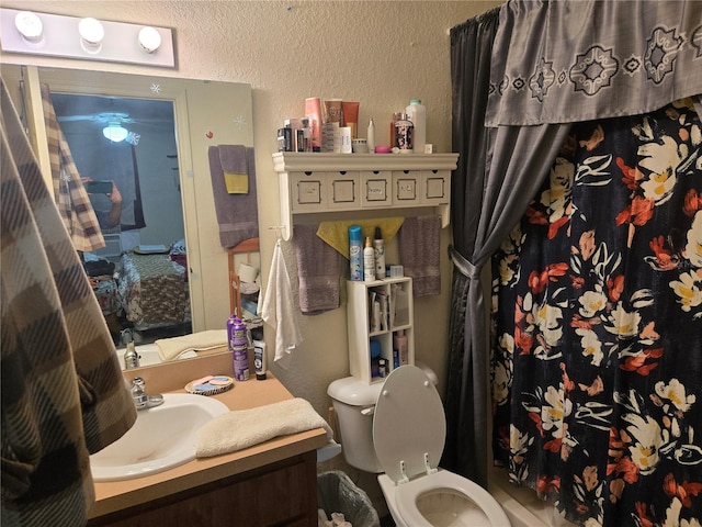 full bath with a textured wall, vanity, and toilet