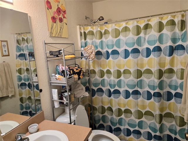 full bathroom with curtained shower, a textured wall, vanity, and toilet