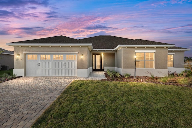 view of front facade with a front yard, decorative driveway, an attached garage, and stucco siding