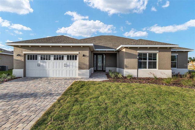 view of front facade featuring a garage, a front lawn, decorative driveway, and stucco siding