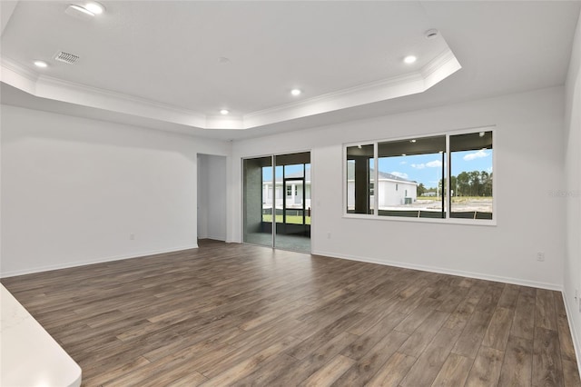 empty room with dark wood-type flooring, a tray ceiling, a wealth of natural light, and visible vents