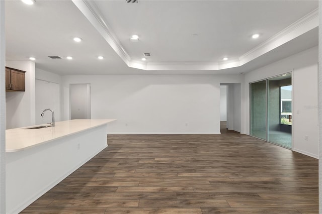 interior space with recessed lighting, a raised ceiling, dark wood-type flooring, ornamental molding, and a sink