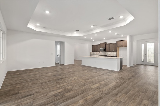 unfurnished living room with dark wood-type flooring, a raised ceiling, and visible vents