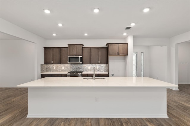 kitchen featuring a sink, visible vents, stainless steel appliances, and a large island with sink