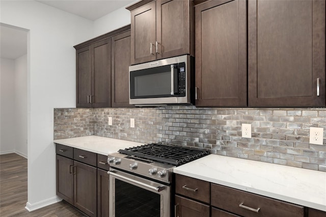 kitchen featuring baseboards, appliances with stainless steel finishes, dark wood-style flooring, dark brown cabinets, and backsplash