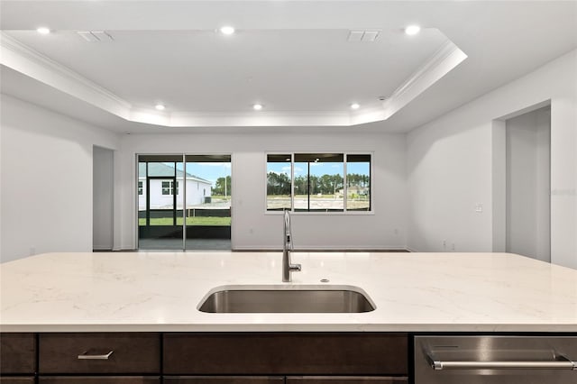 kitchen with light stone counters, a raised ceiling, and a sink