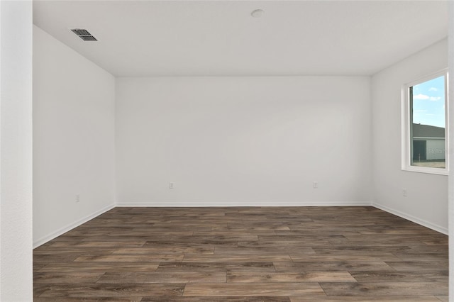 empty room with dark wood-style floors, baseboards, and visible vents