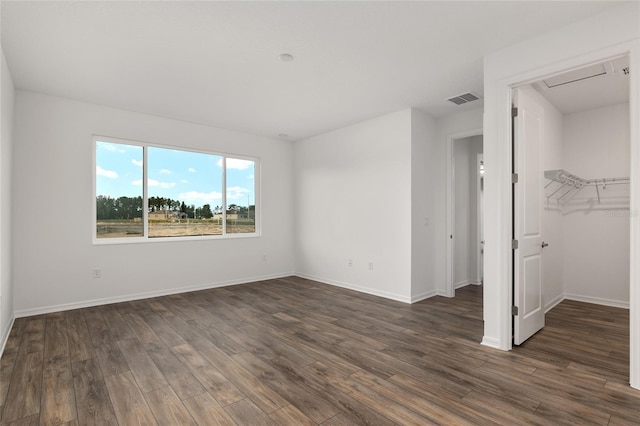 unfurnished bedroom with dark wood-style floors, visible vents, and baseboards