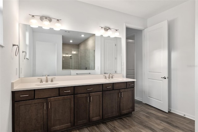 full bath with double vanity, a sink, and wood finished floors