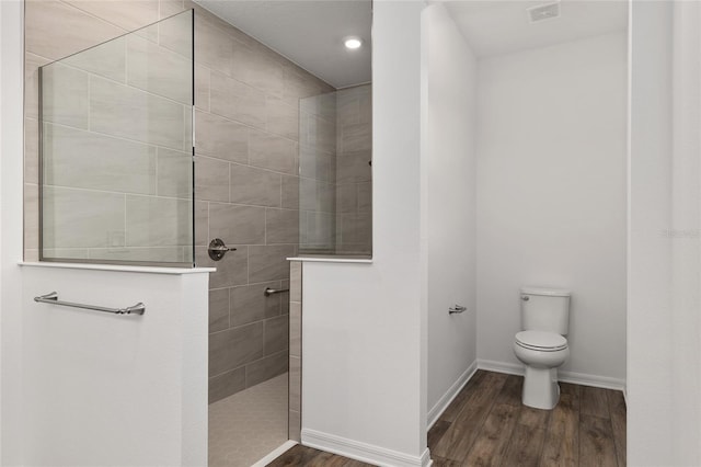 bathroom with baseboards, walk in shower, toilet, and wood finished floors