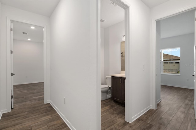 hallway with dark wood-type flooring, recessed lighting, visible vents, and baseboards