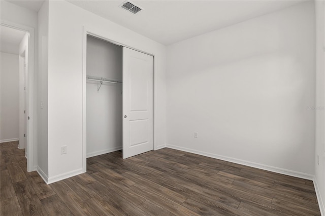 unfurnished bedroom with a closet, visible vents, dark wood finished floors, and baseboards