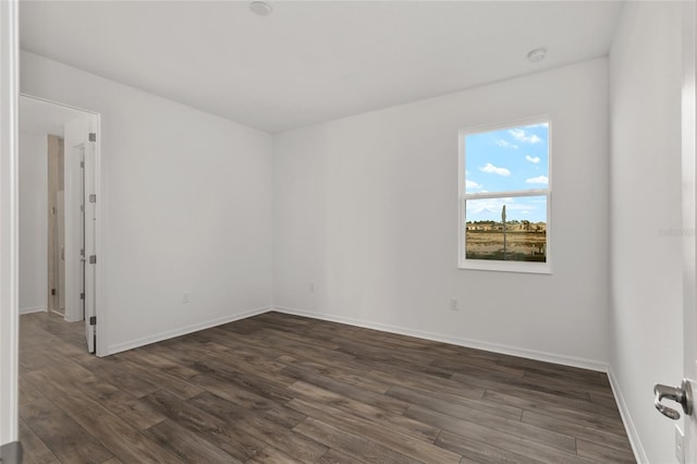 unfurnished room with dark wood-style floors and baseboards